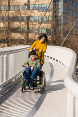 Obraz premium Mother pushing son with cerebral palsy in wheelchair on a bridge