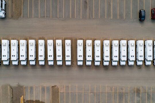 Aerial view of many white vans or buses in a parking lot