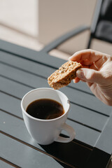 Dipping and eating South African baked rusk in black coffee