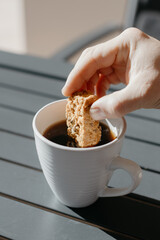 Dipping and eating South African baked rusk in black coffee