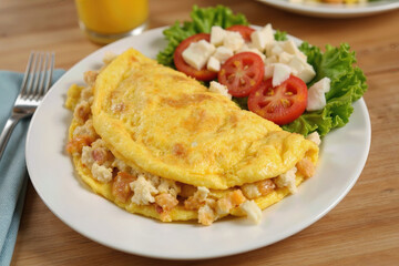 A hearty and protein-packed breakfast featuring a fluffy folded omelette filled with savory ingredients, served with a fresh side salad for a healthy start to the day.
