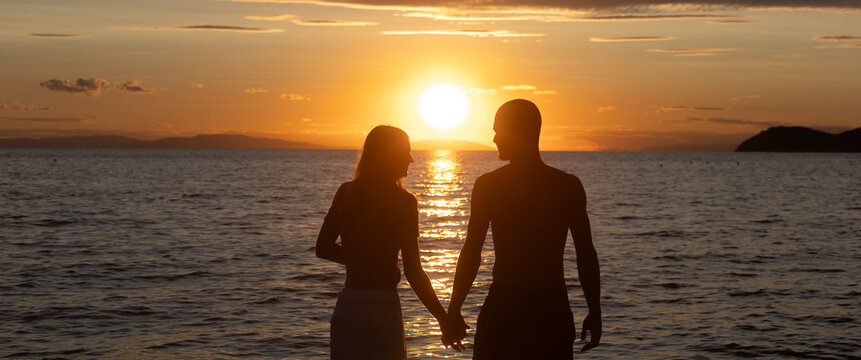 Young couple holding hands at sunset on a beach in Thassos, Greece