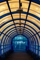 Fotobehang Gang Blue tunnel with a window in the middle. The tunnel is lit up with lights. The tunnel is long and narrow  © Semiglass