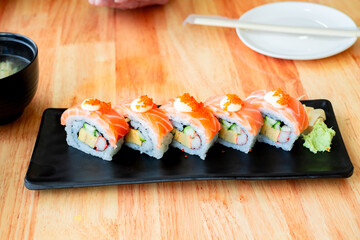Fresh and colorful sushi roll with salmon, tamago, crab stick, cucumber, and rice, served on a white plate. Perfect for Japanese cuisine, food menu, or restaurant promotions