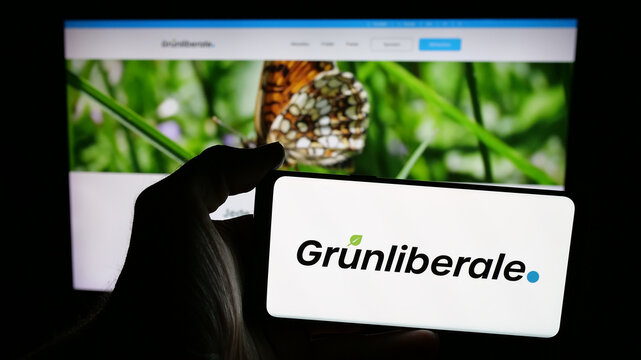 Stuttgart, Germany - 07-30-2025: Person holding mobile phone with logo of Swiss party Gr&uuml;nliberale Partei Schweiz (GLP) on screen in front of web page. Focus on phone display.