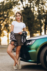 Young woman driver standing by her car