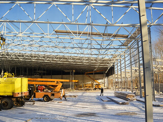 A new industrial building under construction with steel framework and cranes.