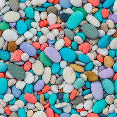 A high-angle shot shows a collection of smooth, colorful pebbles on a beach.

