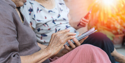 Asian elderly woman using a smartphone interacts with the screen or taking selfie reflecting the growing connection between seniors and digital technology.