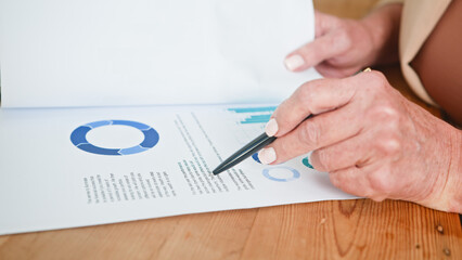 Senior Woman Analyzing Financial Report with Graphs and Charts