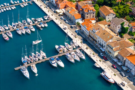 Aerial view of marina with boats and yachts docked along the promenade in a coastal town. Concept of travel, leisure and nautical lifestyle