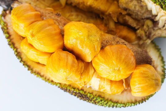 Closeup of a fresh cempedak (or chempedak) fruit, cut open to reveal the bright yellow, sweet, and aromatic pulp and seeds inside.