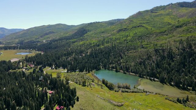 Aerial drone footage of a small village nearby the lake with pine forest and green mountain surrounded. Spring landscape near Durango in southwest Colorado, USA.