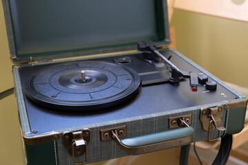Retro portable record player in a suitcase case with open lid, empty platter, tonearm and controls. Vintage analog audio gear for home music listening or product catalog use © RollAndSnap