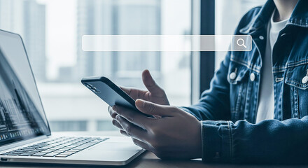 Person using smartphone and laptop with search bar overlay