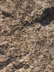 Close-up natural rock surface texture with rough details and earthy tones, perfect for backgrounds, 3D texture mapping, architectural design references, and geology or nature-related concepts.