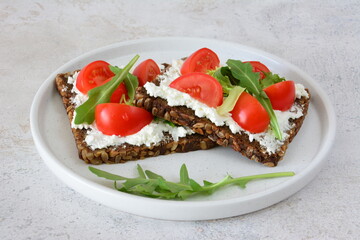 Healthy snack with tomatoes, ricotta cheese and arugula on a plate