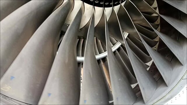 Close-up view of airplane engine fan blades rotating slowly, showcasing smooth mechanical motion, precision engineering, aerodynamic design, and advanced aviation technology