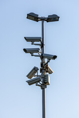 Multiple CCTV security cameras and lights on a tall pole. Concept of public surveillance, safety, monitoring, and privacy.