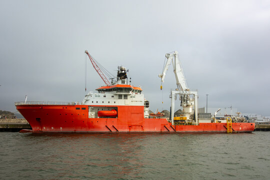 Modern offshore support vessel. Large red industrial ship with crane and lifeboat. Maritime transport and logistics for the oil and gas energy industry.