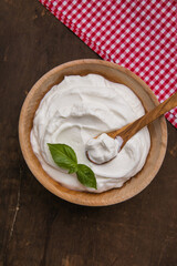 Plain greek yogurt in wooden bowl  on wooden board
