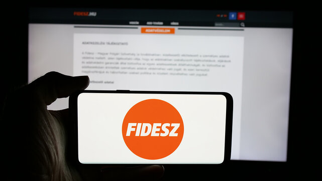 Stuttgart, Germany - 08-01-2025: Person holding cellphone with logo of party Fidesz - Magyar Polgari Szovetseg on screen in front of webpage. Focus on phone display.
