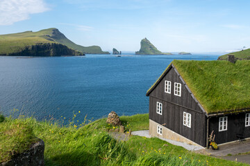 Stunning coastal view of the Faroe Islands with traditional grass-roofed house by the sea