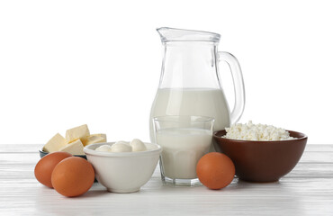 Different dairy products and eggs on wooden table against white background