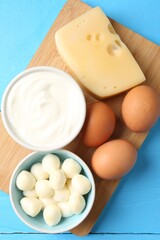 Different dairy products and eggs on light blue wooden table, top view