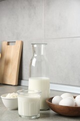 Different dairy products and eggs on gray textured table in kitchen