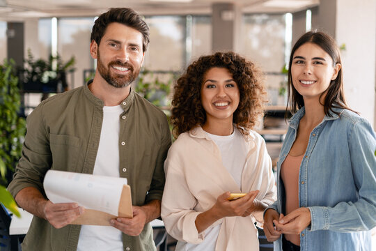 Smiling businesspeople holding documents and smartphone in office