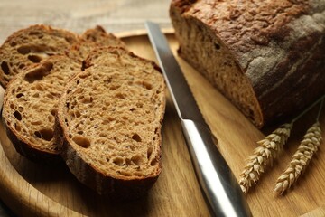 Pieces of fresh bread, spikes and knife on table, closeup