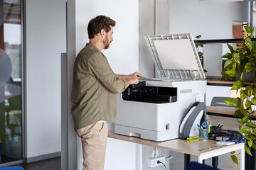 Office worker fixing printer in modern office