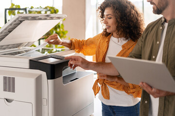 Business colleagues using a modern multifunction printer in the office