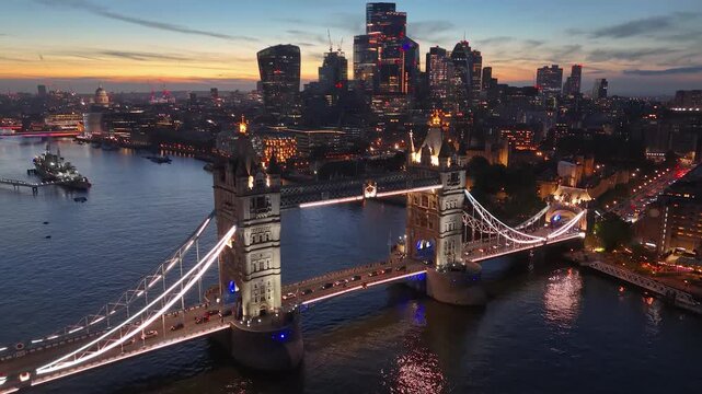 Aerial view of illuminated tower bridge over thames river with london skyline at night, london, england, united kingdom.