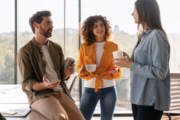 Coworkers chatting and drinking coffee during a break in the office
