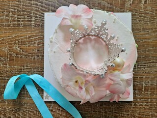 Fresh whipped cream cake decorated with real pink floral petals, edible white pearls and small Tiara on the wooden table - closeup © Kpictures