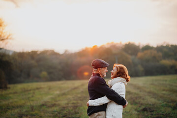 Senior couple embracing in autumn sunset light.