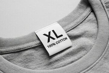 Close-Up of an XL Size Tag on a Gray Cotton T-Shirt Displaying Fabric Composition and Garment Size Information for Apparel Manufacturing