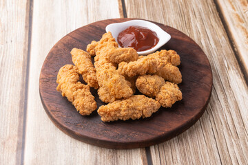 Breaded chicken bites in a board over wooden table