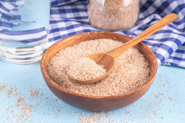 Whole Psyllium Husk in spoon, bowl and jar, with glass of water, natural alternative to pills or injections for weight loss. Additional fiber source, adsorbent, dietary supplement for healthy eating