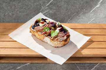 Duck bruschetta with berry jam on artisan bread, bright daylight, overhead composition