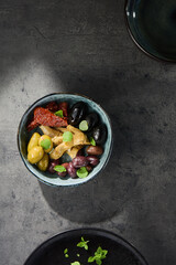 Antipasti bowl with olives, sun-dried tomatoes, and artichokes in bright overhead minimal composition