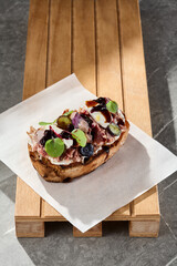 Duck bruschetta with berry jam, bright lighting, overhead composition on wood and paper