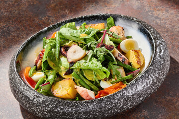 Grilled octopus salad in bright overhead composition with rustic mood and artisanal stoneware