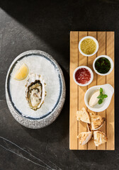 Oyster on ice, bright mood, overhead composition with sauces, lemon, and toasted bread sides