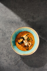 Tom yum soup with seafood, bright overhead lighting, centered minimal composition