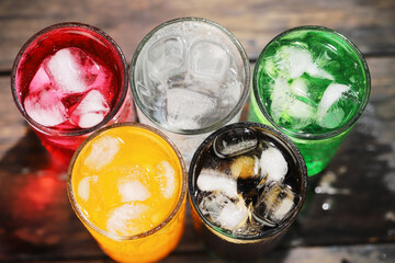 Soft drinks and fruit juice mixed with soda high in sugar have a negative effect on physical health. on the table wood.