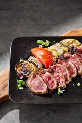 Roast beef sliced with grilled vegetables on bright rustic overhead composition
