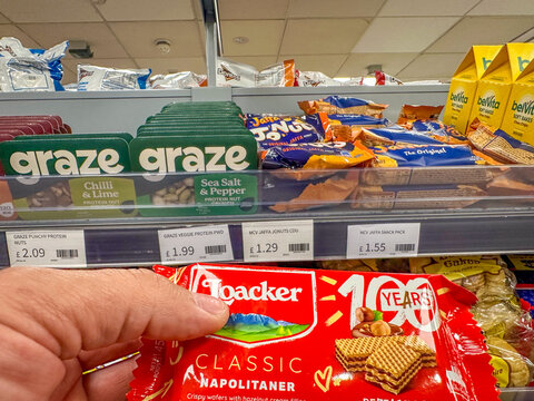 Loacker Classic wafer snack held in hand near supermarket shelf stocked with Graze savory snack boxes
